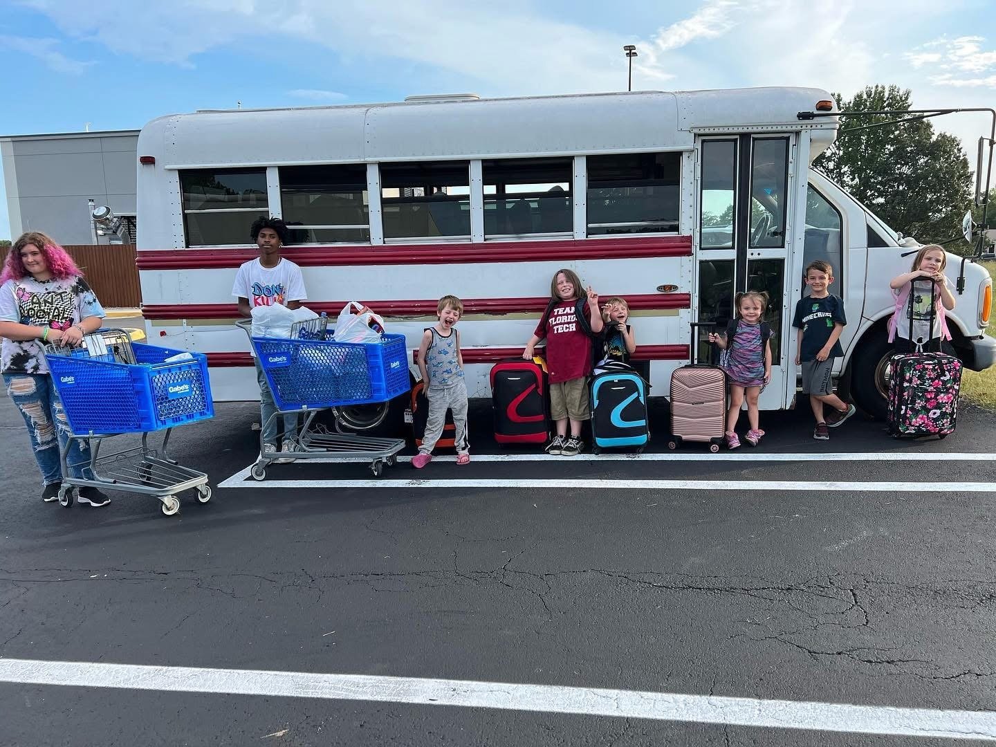 Happy Movers helping kids with luggage and school supplies in front of the bus