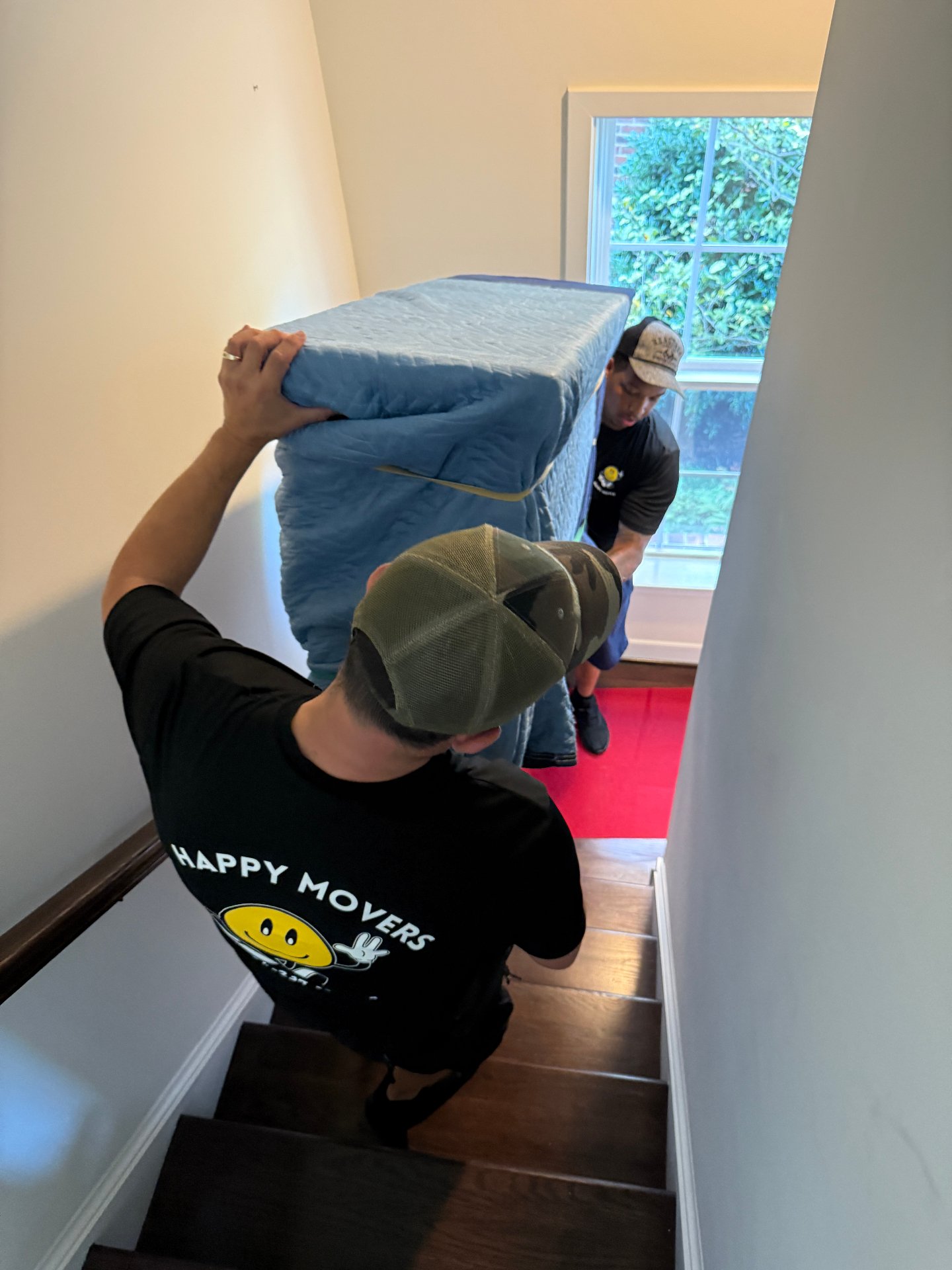 Happy Movers carrying a mattress up the stairs
